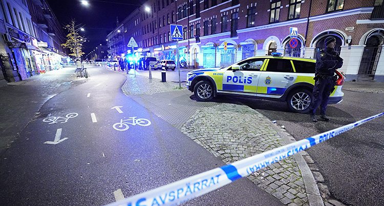 En polis står vid en bil. Det är mörkt.