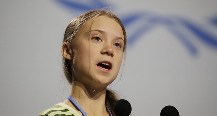Greta Thunberg talar. Hon har en mikrofon framför sig.