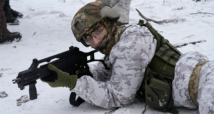 En soldat med vapen krälar på marken i snö.