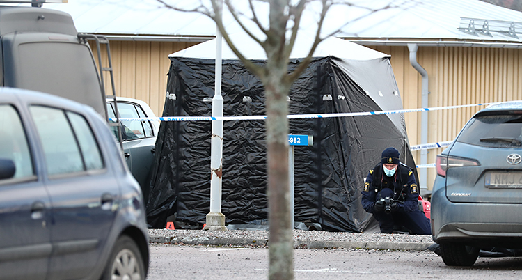 Poliserna har satt upp ett tält på platsen där en person blev skjuten. En polis jobbar vid tältet.