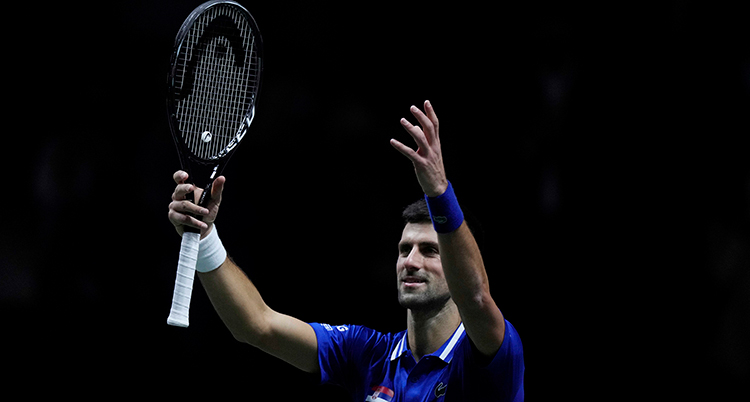 Novak Djokovic spelar tennis. Han lyfter sina händer.