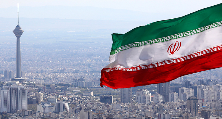 Huvudstaden Teheran fotad uppifrån, nära en Iransk flagga som fladdrar i vinden.