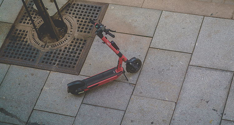 En sparkcykel på el står parkerad på en trottoar.