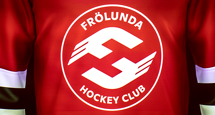 En röd märke. På tröjan är det ett märke i vitt och med vit text står det Frölunda Hockey Club.