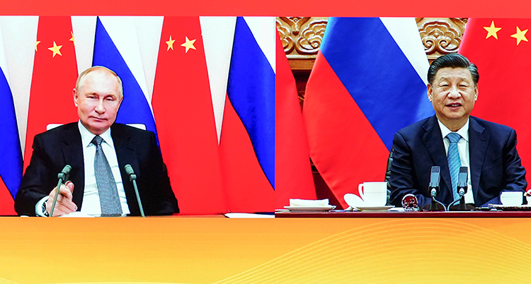 Putin bredvid Xi Jinping vid ett långt bord. Bakom dem en röd fondvägg och flera av ländernas flaggor.