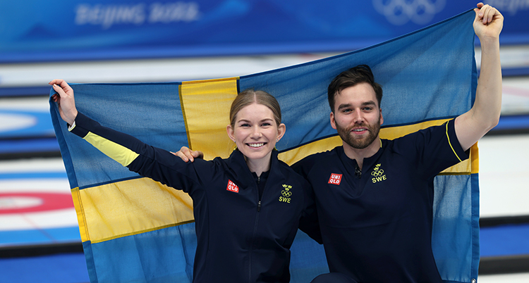 De sitter på huk och håller upp en svensk flagga bakom sig.