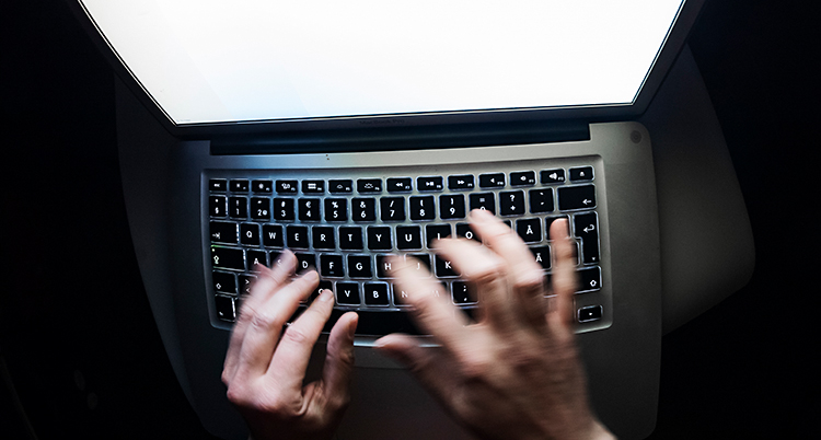 Två händer som skriver på en dator.