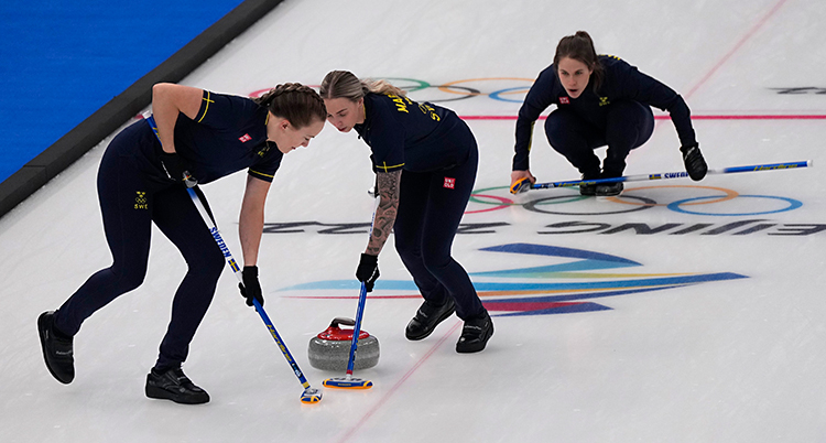 Tre kvinnor spelar i en match i curling.
