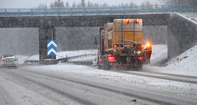 En lastbil på E18 kör i snöovädret.