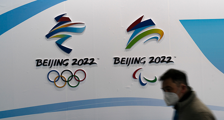 En man framför en skylt med de olympiska spelens logga.