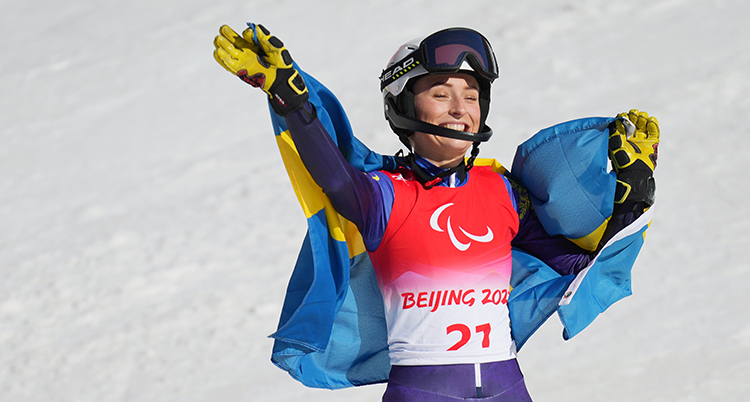 Ebba Årsjö vinkar till publiken med en flagga över axlarna.
