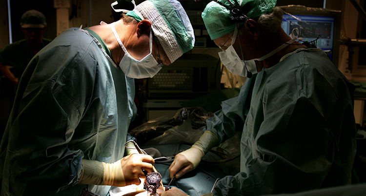 Två läkare i grönt gör en operation på en patient.