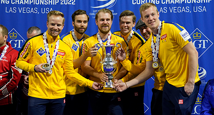 Bilden visar herrarna i Sveriges lag i curling. De är glada. De har gula kläder. De har fått guldmedaljer.