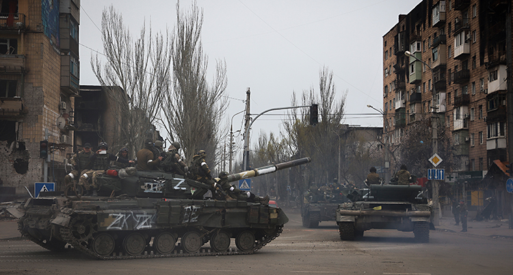 En gata i staden Mariupol. Ryska stridsvagnar åker genom staden. Det sitter soldater på stridsvagnarna.