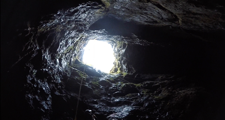 Någon har fotograferat från botten av ett hål. Man ser klippvägarna och längst upp syns ljuset vid markytan.