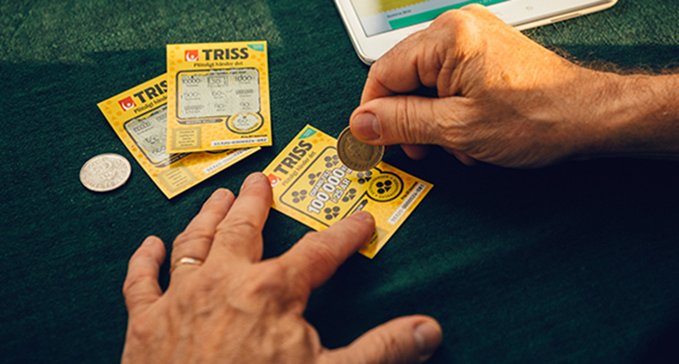 En person skrapar lotter med mynt