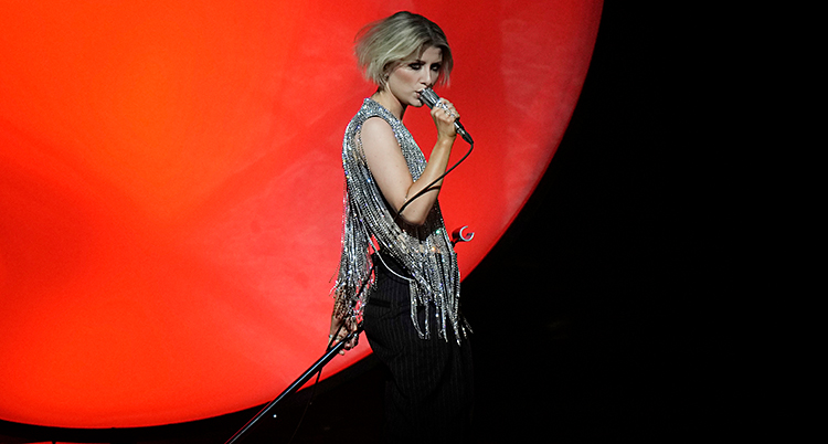 Hon står på en scen och sjunger i en mikrofon.