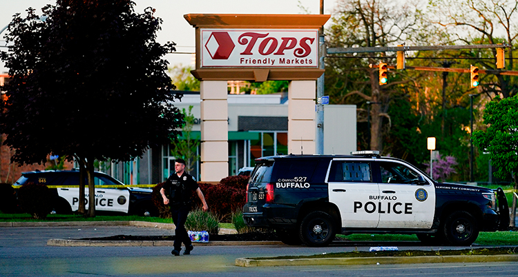En polis går nära sin bil. I bakgrunden syns en skylt med en affärs logga.
