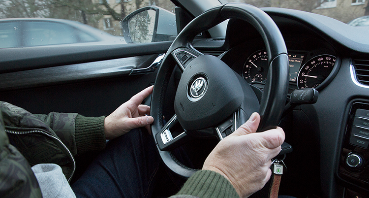 En person håller sina händer på ratten i en personbil. Hastighetsmätaren visar 40.