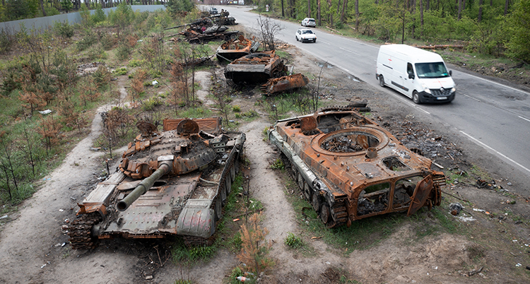 Förstörda pansarvagnar står vid en väg.