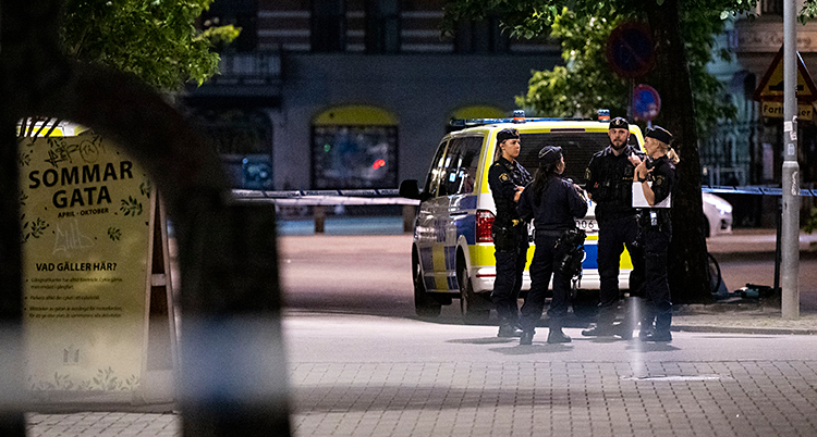 Några poliser står på en gata på natten.