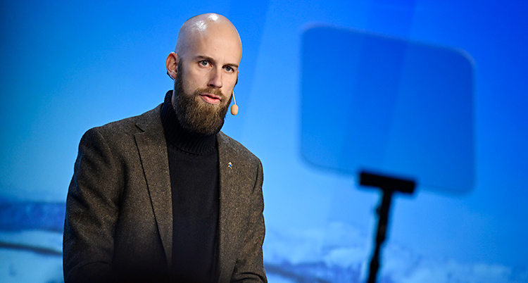 Han står på en scen och pratar i en mikrofon.