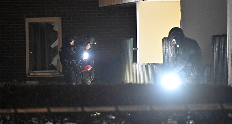 Poliser med hjälmar lyser med ficklampor.