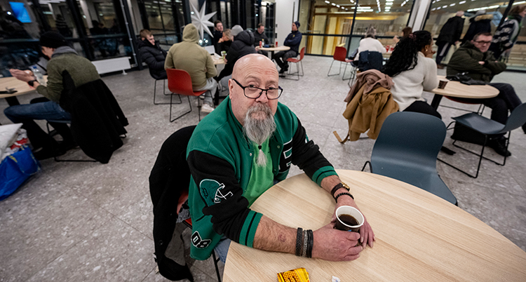 Han sitter vid ett bord och dricker te.