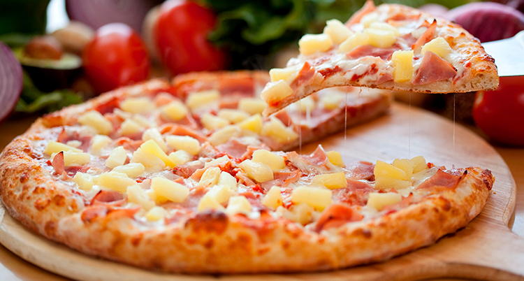 Någon lyfter en bit från pizzan.