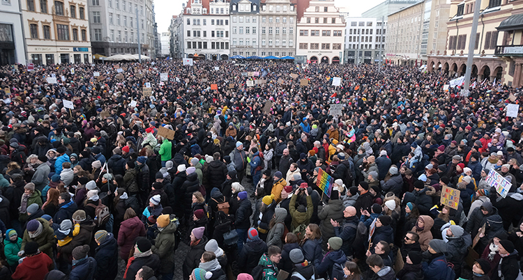 Massor av människor står på ett torg.