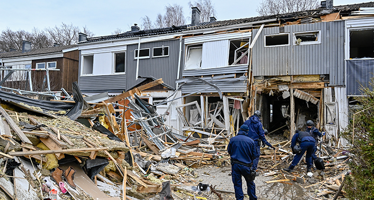 Poliser framför det förstörda huset.