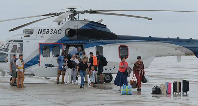 Några människor kommer ut ur en helikopter som står på marken.