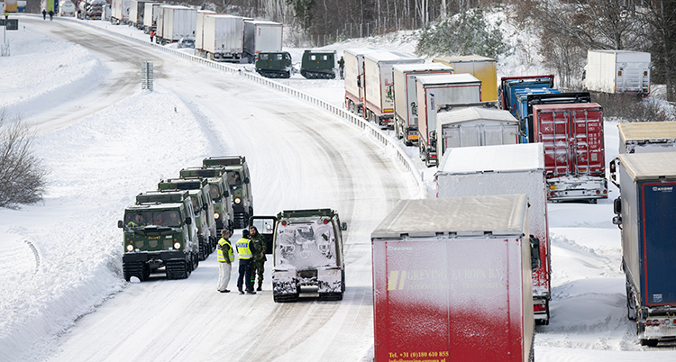 Många lastbilar står i kö på vägen.