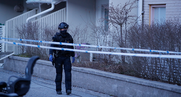 En polis med hjälm framför ett hus.