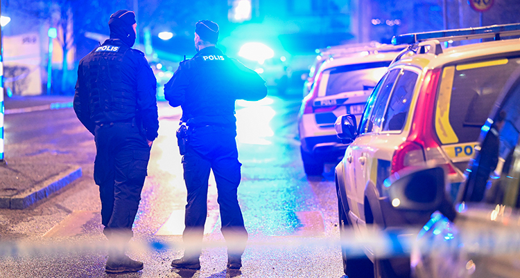 Två poliser står på en gata som är avspärrad.
