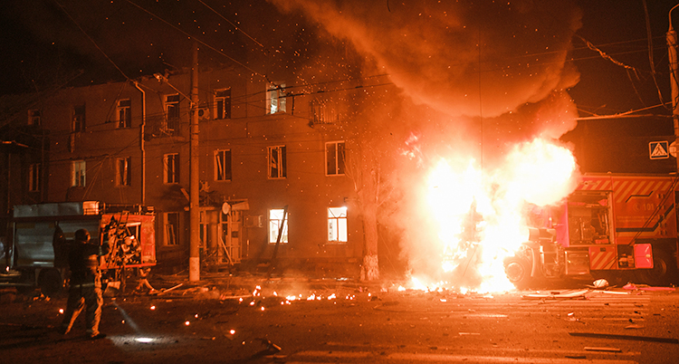 Det är mörkt ute. En brandbil brinner utanför ett hus med lägenheter.