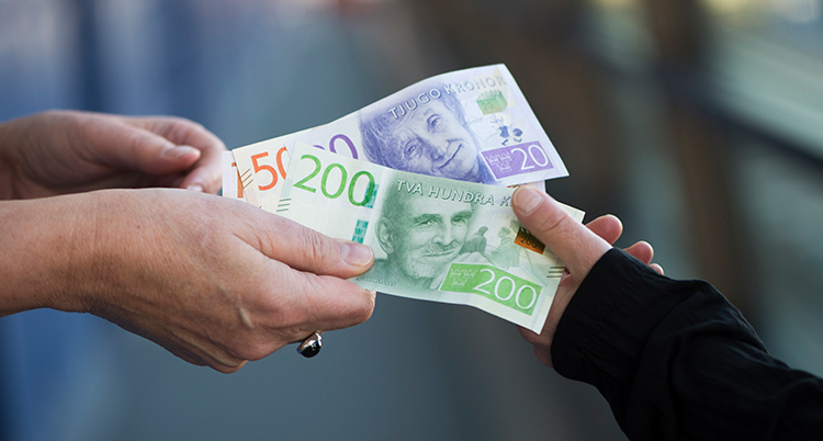 En hand ger sedlar till en annan hand.