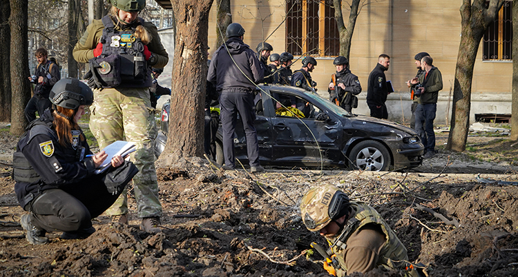 Flera människor i uniformer arbetar på en plats dör en bomb slagit ner.