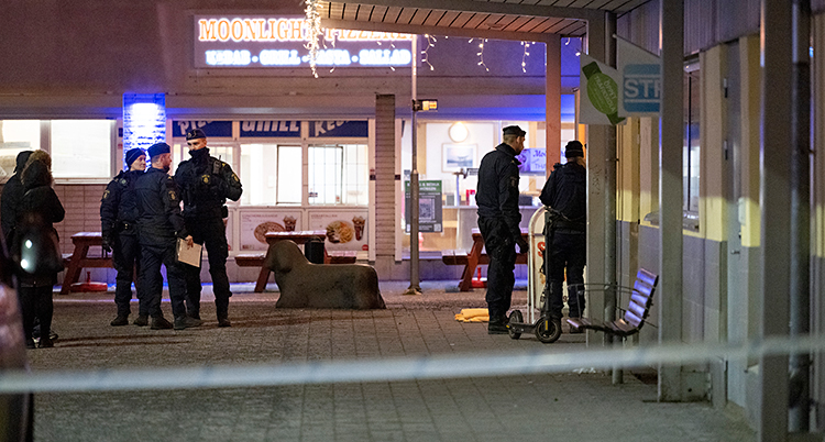 Det är kväll. Flera poliser står utanför en restaurang.