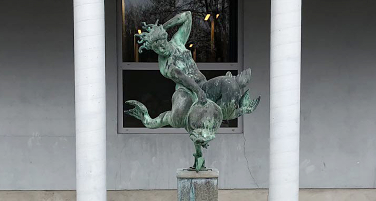 En staty av brons som står utanför ett hus.