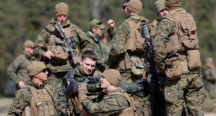 De har militärkläder på sif i brunt och grönt. De håller i stora vapen.