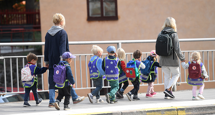 Två vuxna är ute och går med på barn i en förskola.