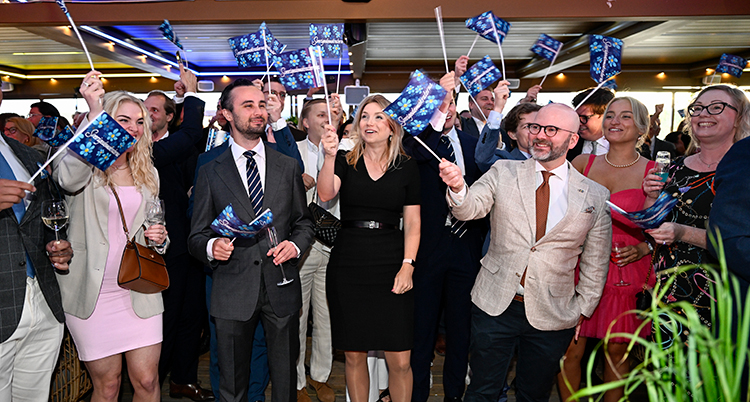 En grupp glada kvinnor och män som viftar med flaggor med SDs logga på.