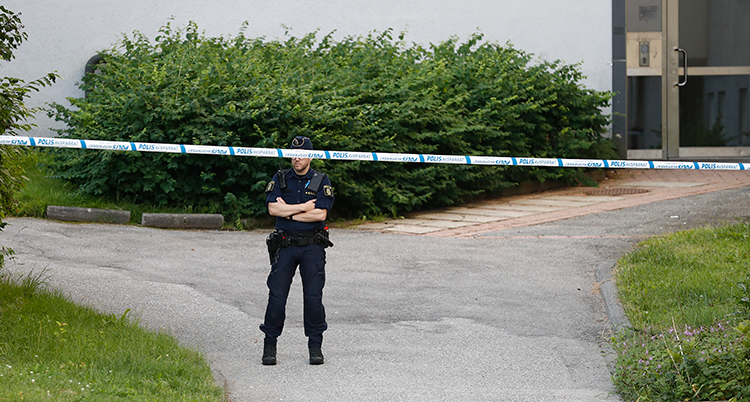 Poliserna har spärrat av utanför ett hus. En polis står och vaktar.