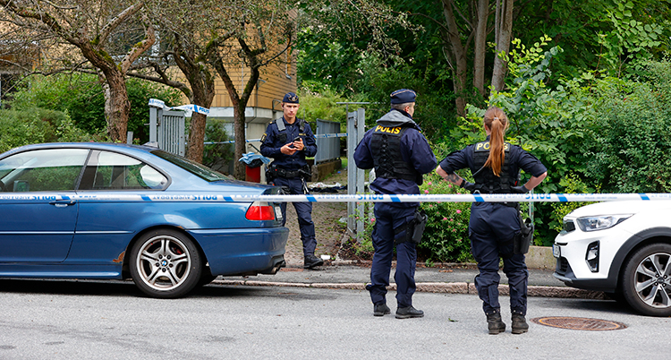 Tre poliser står på en gata.