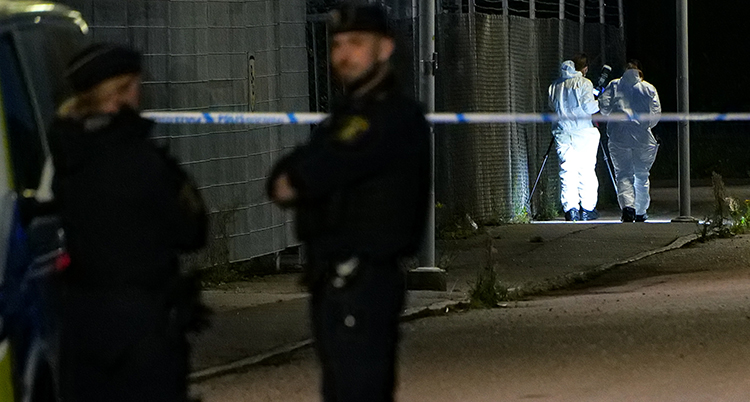 Poliser står vid avspärrande band.
