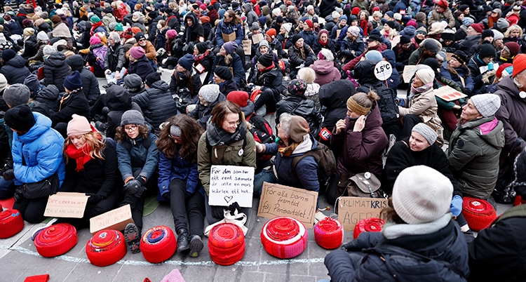Massor av kvinnor sitter ner på ett torg under en protest.