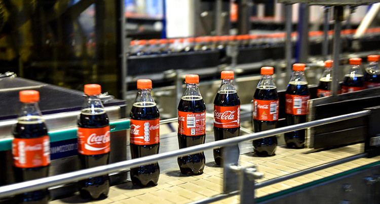 Flaskor med Coca cola åker på ett band i en fabrik.