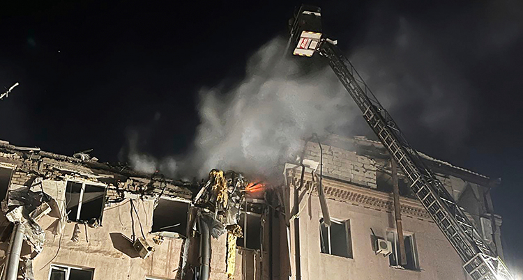 Det ryker från ett hus. Brandmän på en kran med korg jobbar.